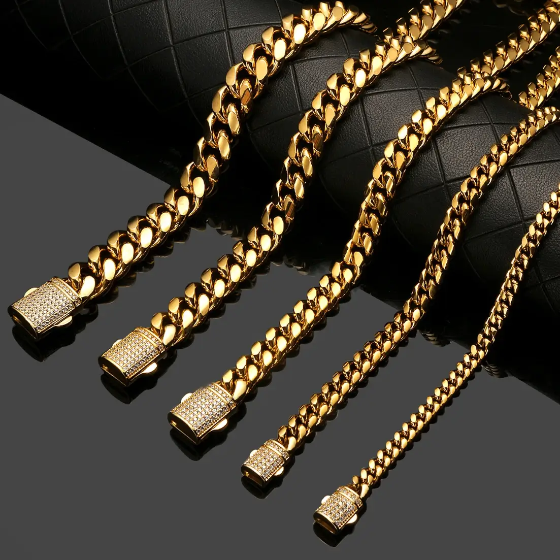 Five gold chain bracelets in varying thicknesses on a black surface.