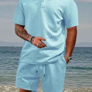 Man in light blue casual outfit standing on the beach.