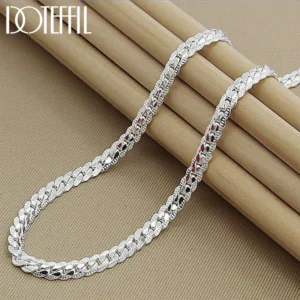 Silver chain necklace on a beige background.