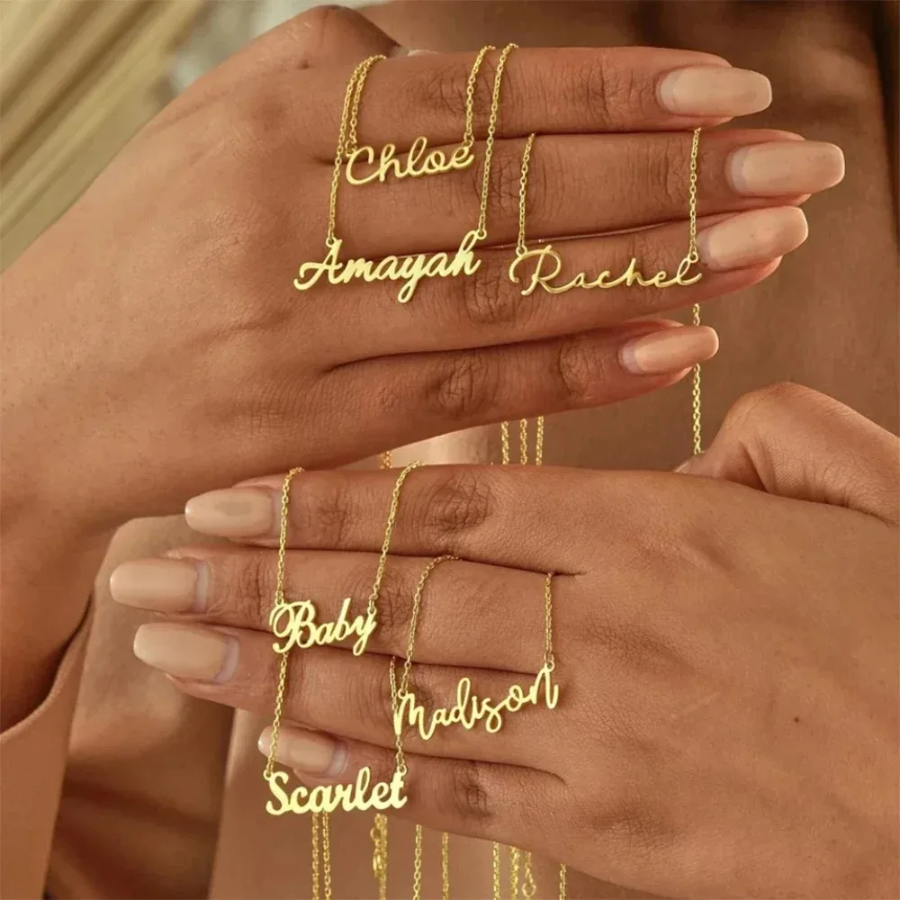 Hands holding gold name necklaces.