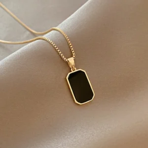 Gold necklace with black rectangular pendant.