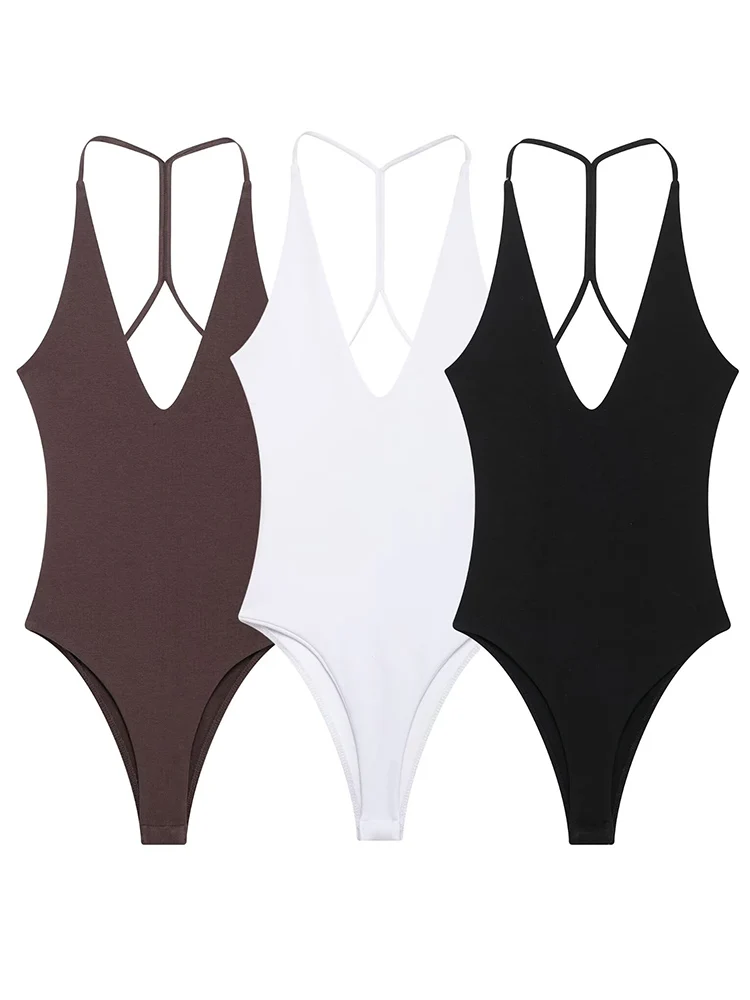 Three stylish one-piece swimsuits in brown, white, and black with crisscross back straps.