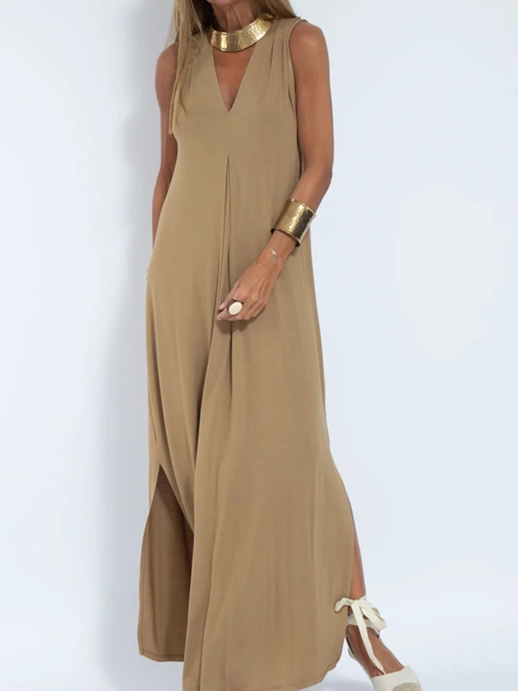 Woman wearing a tan sleeveless maxi dress with side slits.