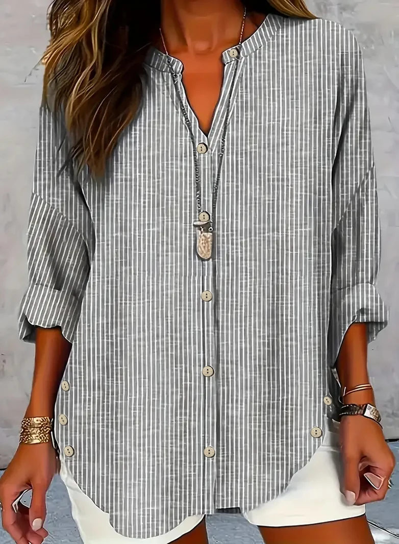 Woman wearing a casual striped button-up shirt with rolled sleeves.