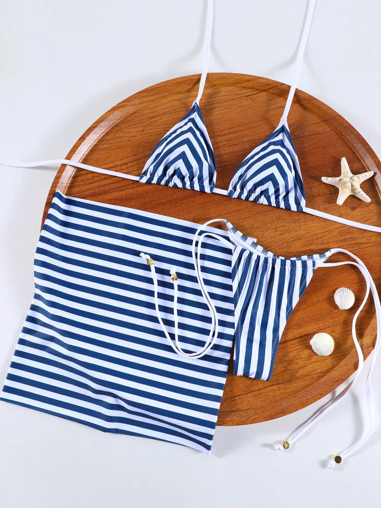 Striped blue and white bikini set with a matching skirt on a wooden tray.