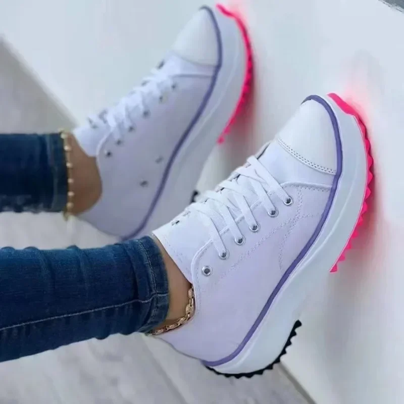 White high-top sneakers with pink and black soles worn with jeans.