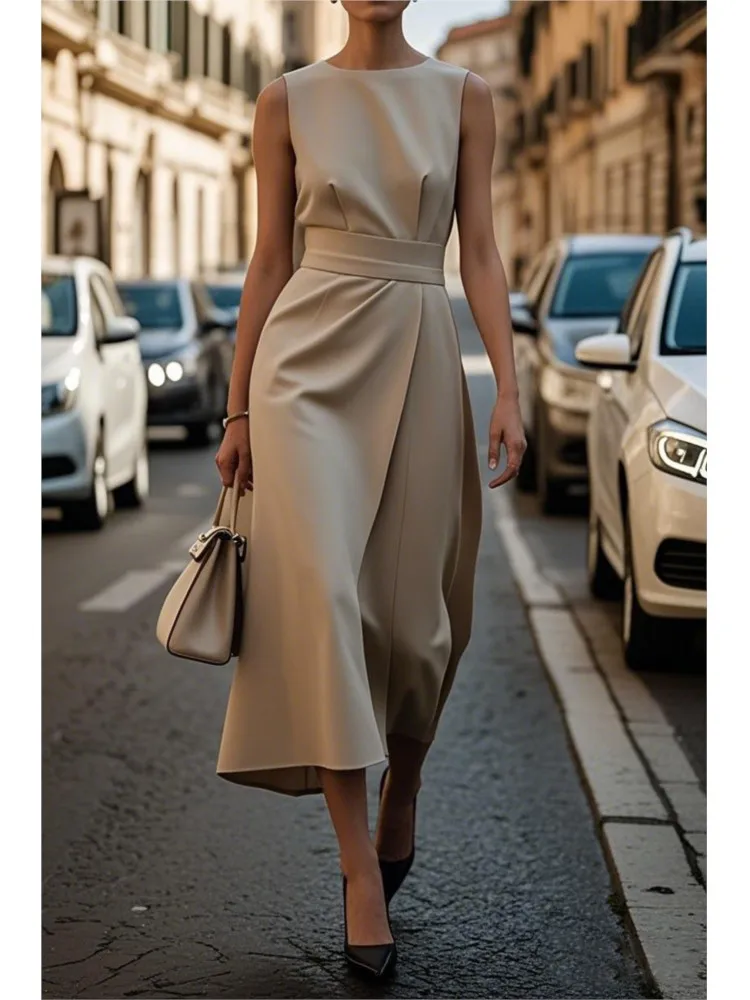 Chic woman in a stylish beige dress walking down a city street with a handbag.