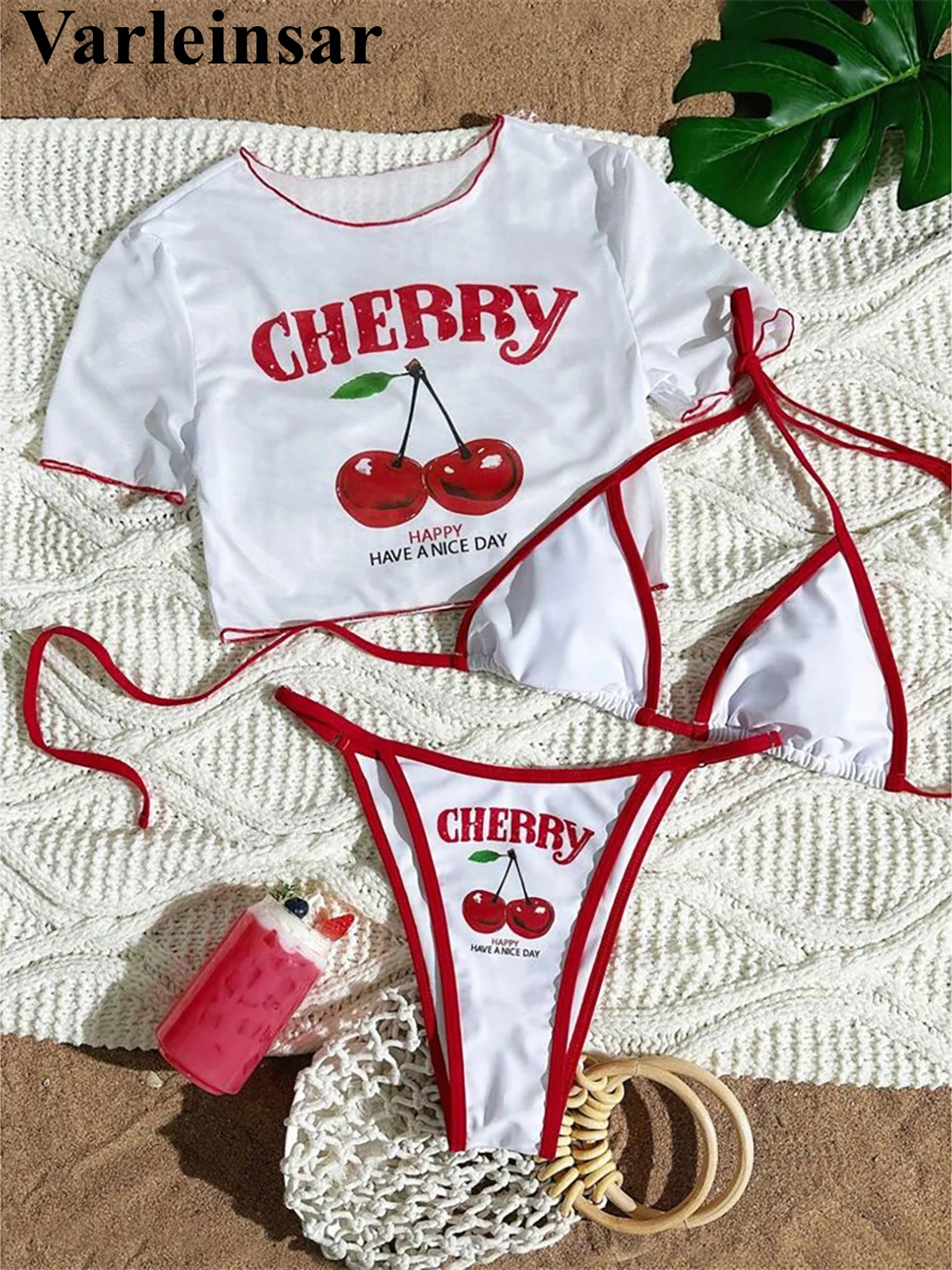White and red cherry-themed bikini set with matching crop top and lip balm.