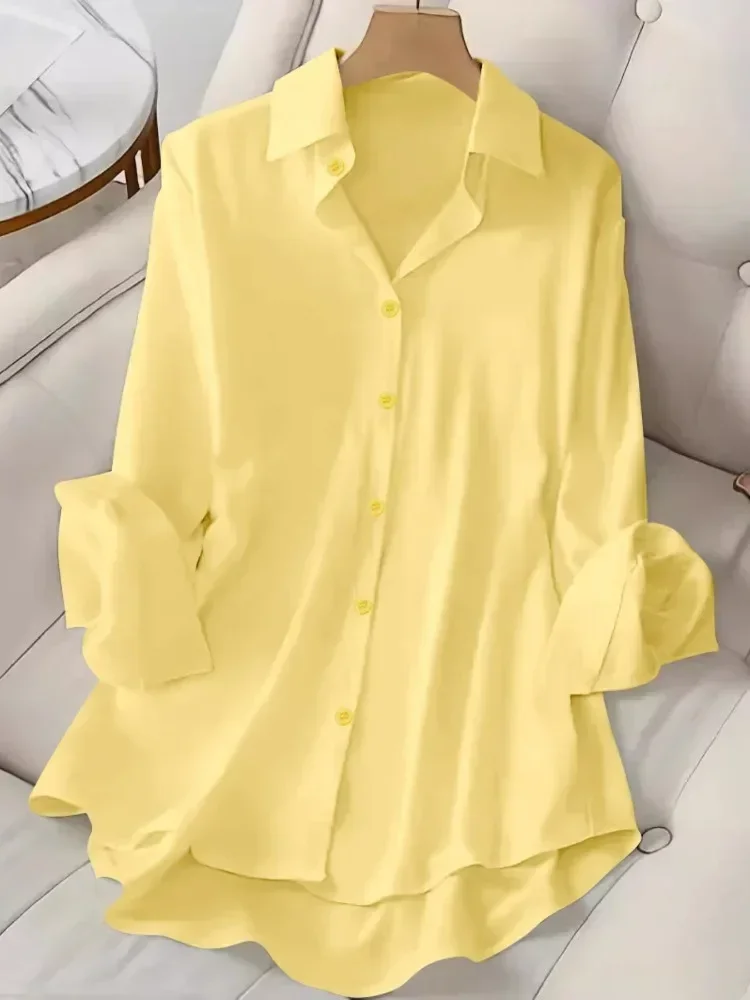 A light yellow button-up shirt with rolled sleeves on a white surface.