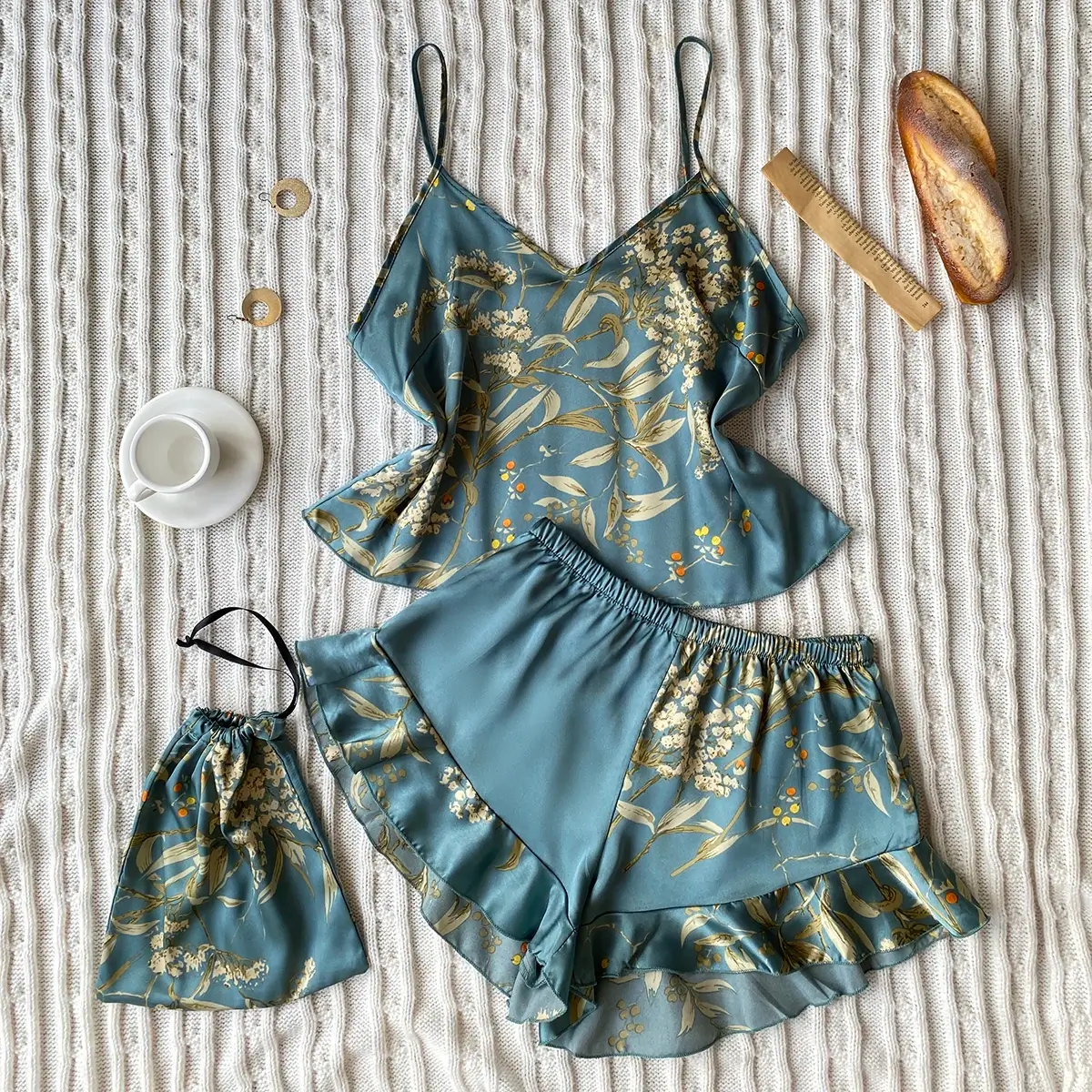 Floral pajama set with camisole, shorts, mask, and slippers on a textured fabric.
