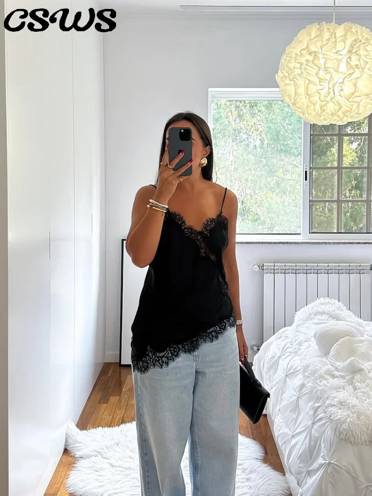 Woman in casual black lace top and light jeans taking mirror selfie.