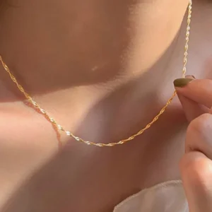 Person wearing a gold twisted chain necklace.