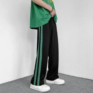 Black pants with green patterned side stripes and white sneakers.