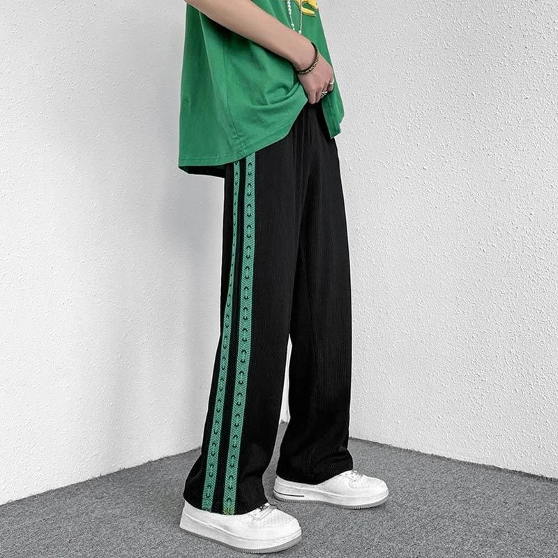 Black pants with green patterned side stripes and white sneakers.