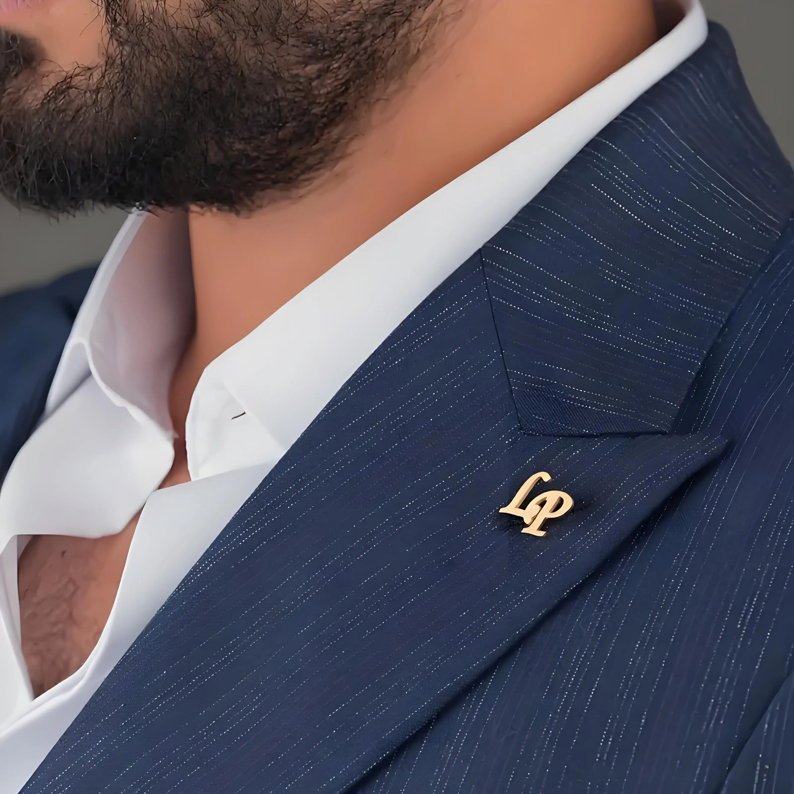 Close-up of a man in a blue suit with a gold lapel pin.