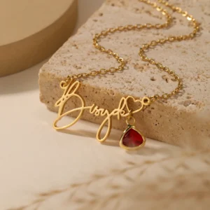 Gold necklace with red heart pendant.