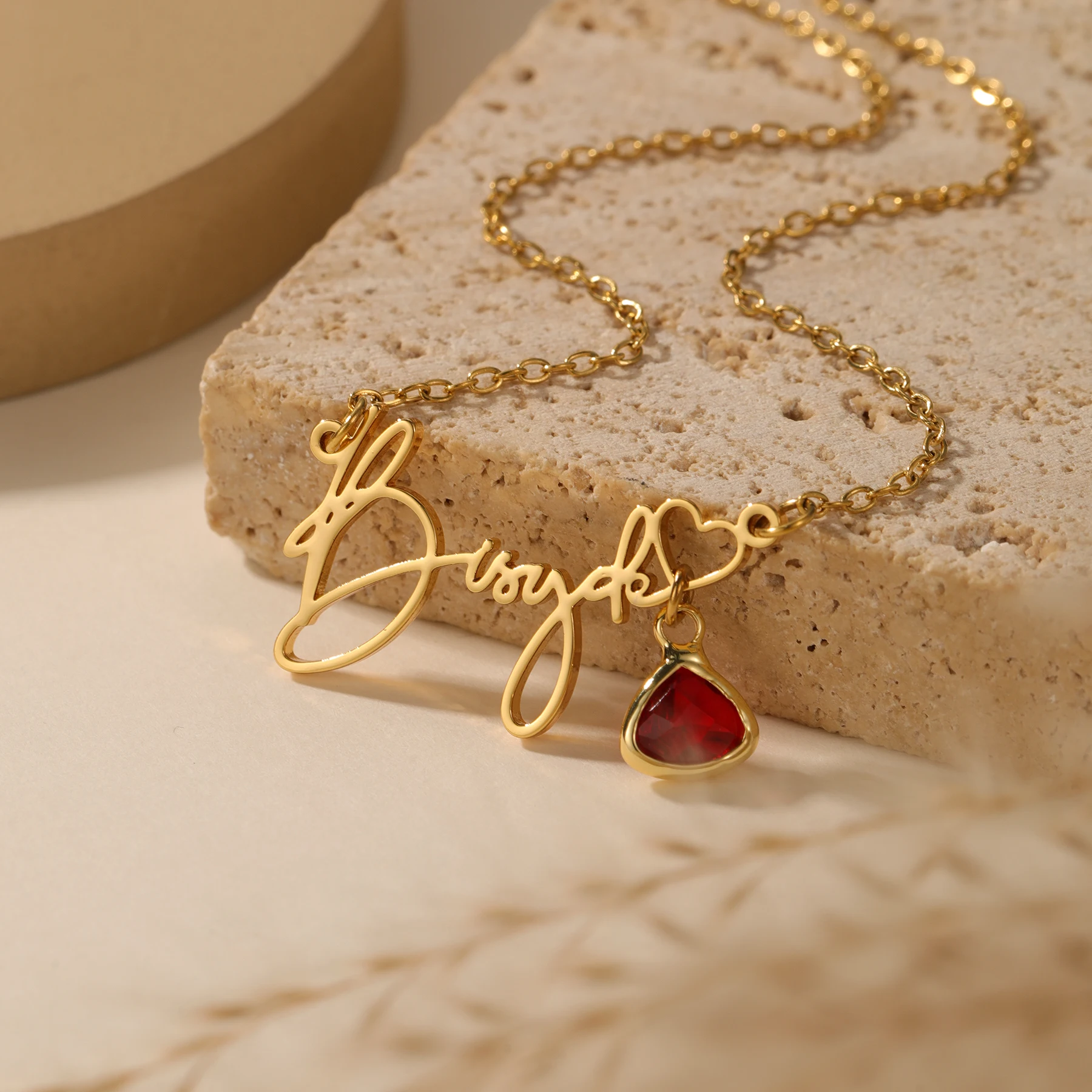 Gold necklace with red heart pendant.