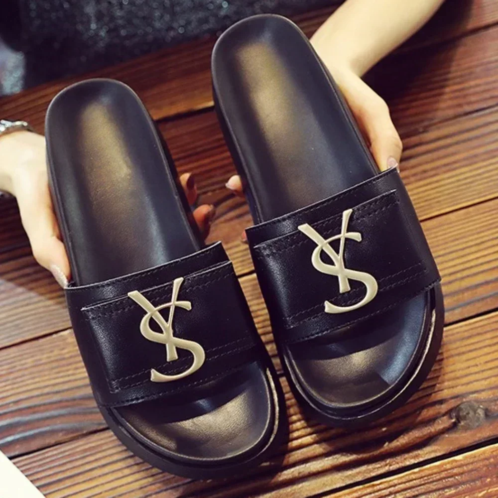 Black slip-on sandals with gold YSL logos.