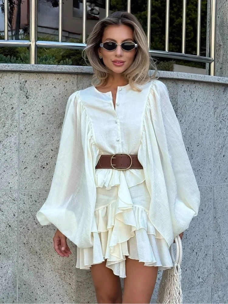 Woman wearing a flowing white dress with a brown belt and sunglasses.