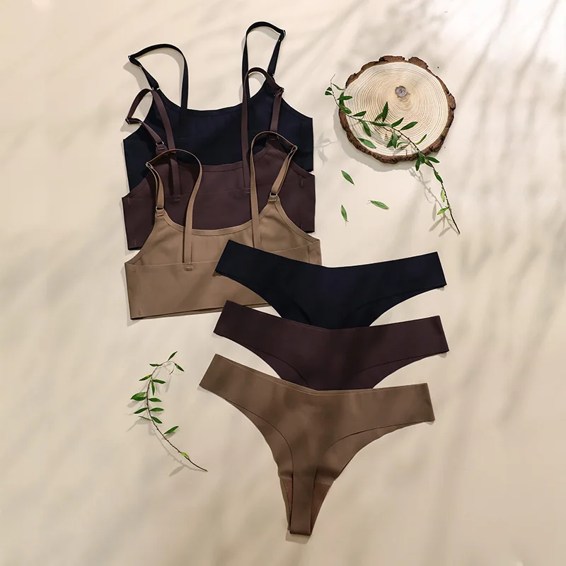 Set of three seamless thong panties in black, brown, and beige with a matching corset top on a fabric background.