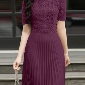 Elegant woman in a purple pleated dress holding a small handbag.