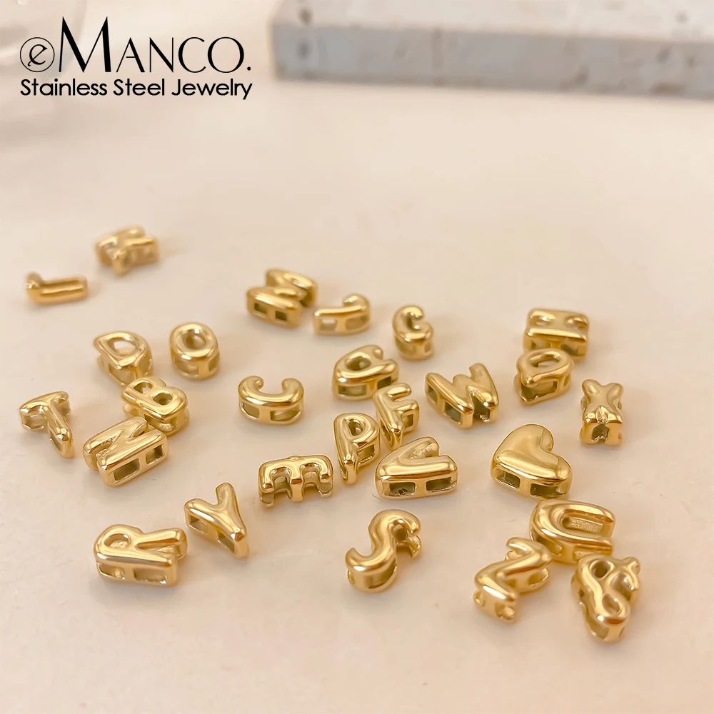 Small gold alphabet charms arranged on a white surface.