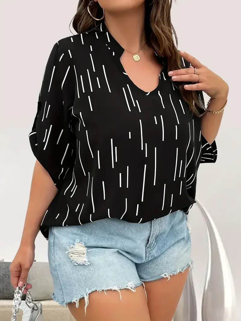 Woman wearing a black patterned blouse and distressed denim shorts.