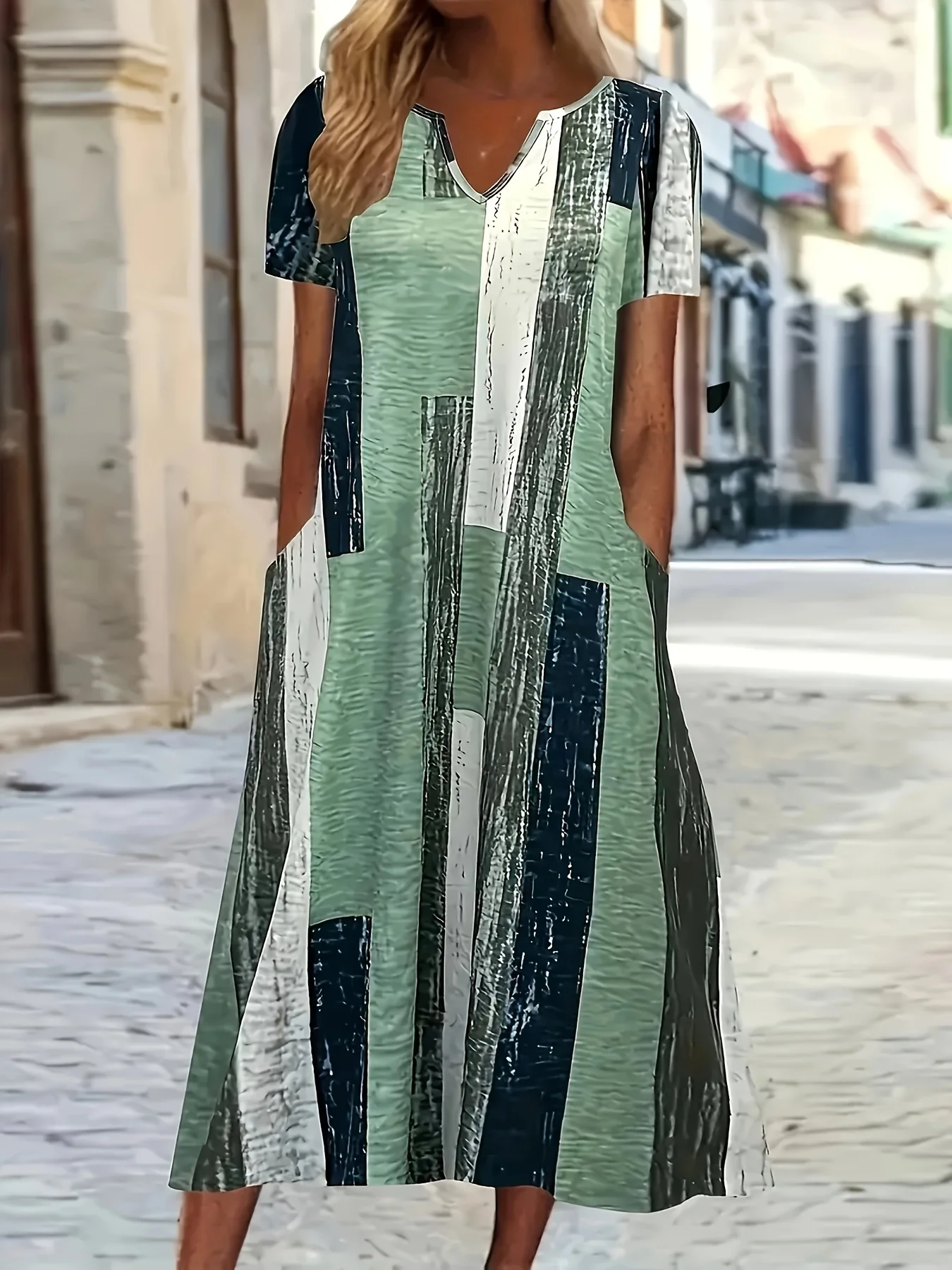 Woman wearing a stylish, long striped dress on a street.