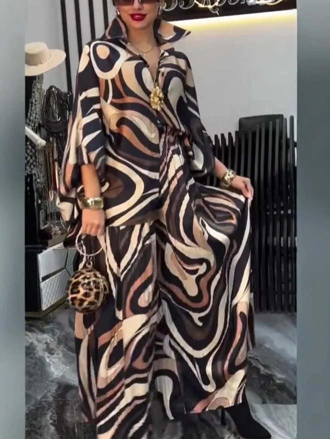 Person wearing a flowing, abstract-patterned dress holding a leopard print bag.