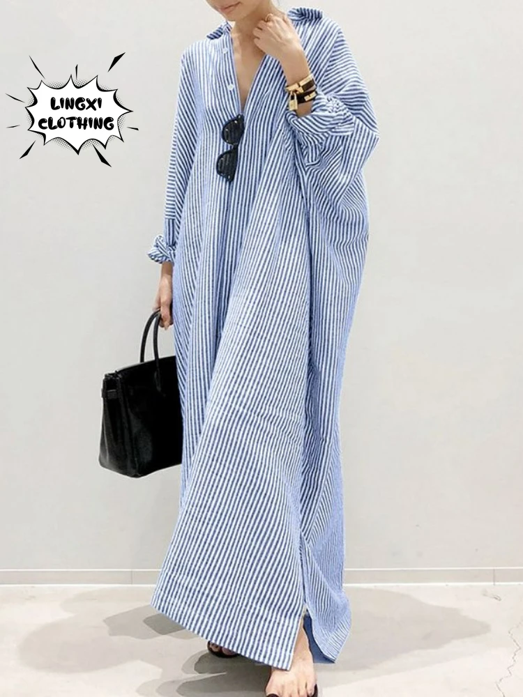 Woman wearing a light blue abaya holding a black handbag.