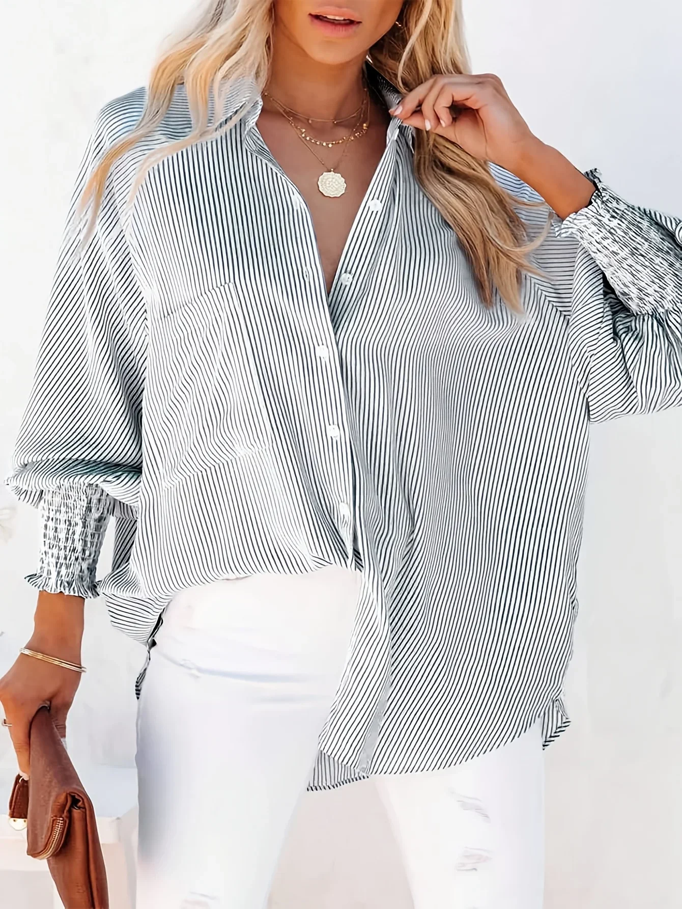 Woman wearing a light gray blouse and white pants.