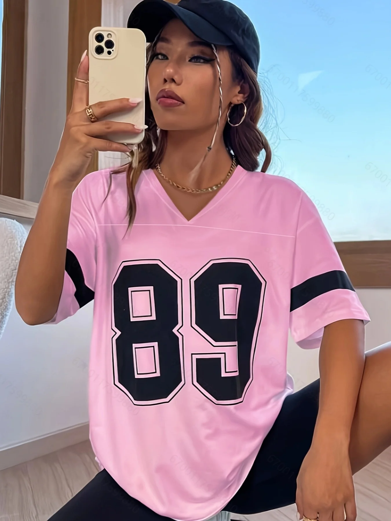 Woman in a pink sports jersey taking a mirror selfie.