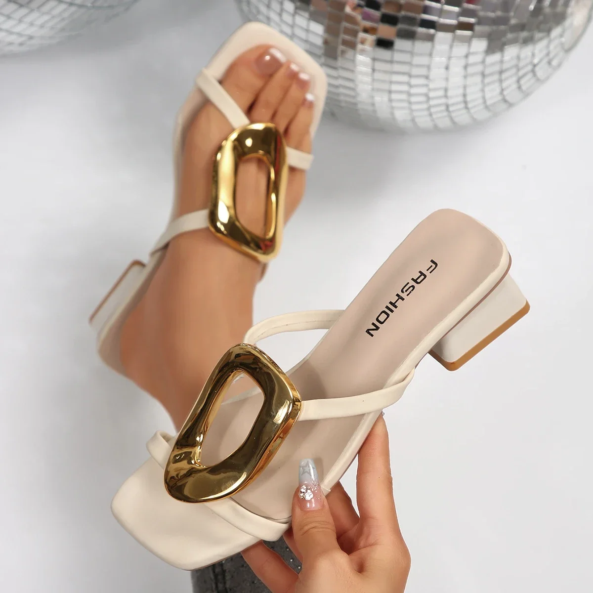 Stylish beige heeled sandals with large gold buckles.