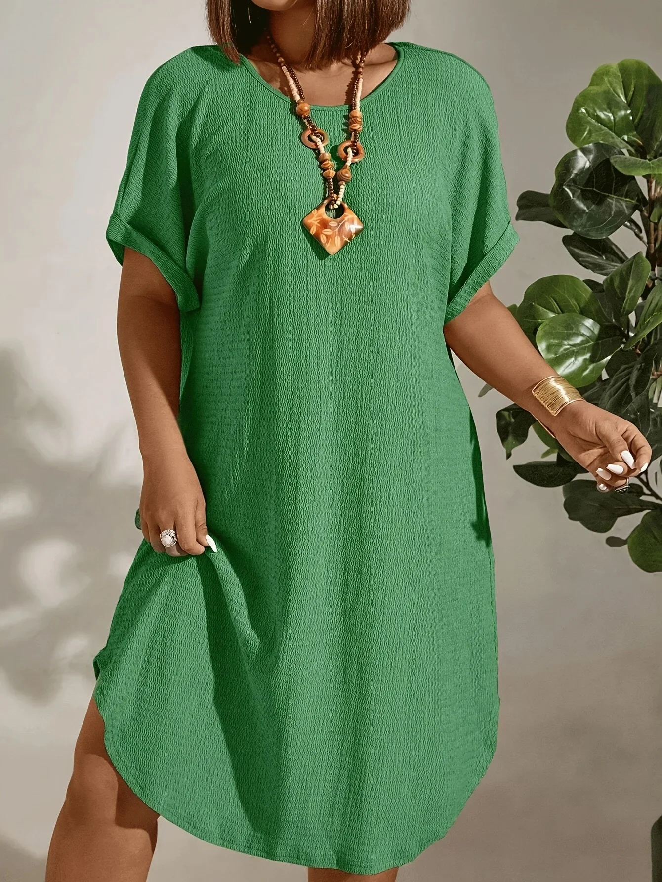 Woman wearing a loose green midi dress with pockets and a necklace.