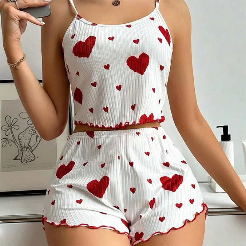 Woman wearing white pajamas with red hearts and ruffled edges.