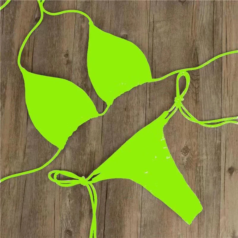 Neon green string bikini laid on wooden floor.