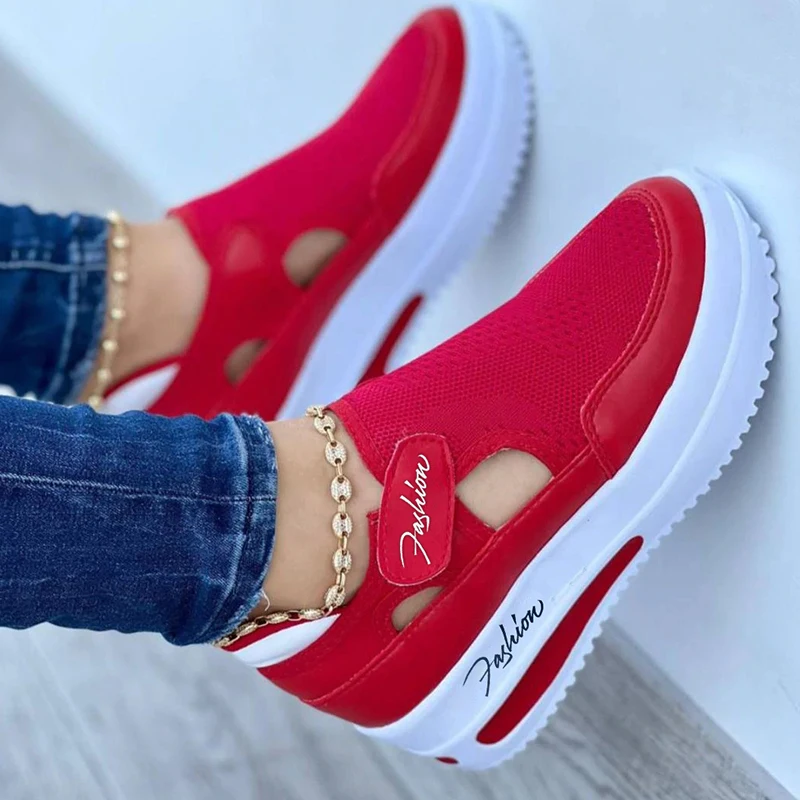 Red slip-on sneakers with white soles worn with jeans.