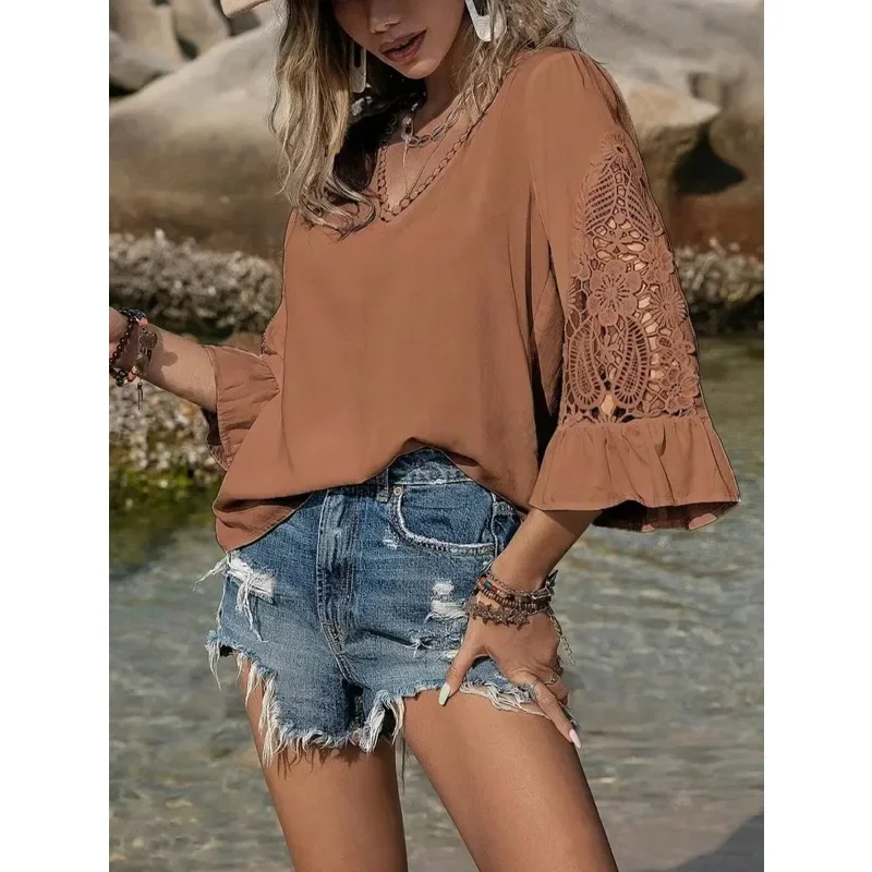 Woman wearing a peach blouse with lace sleeves and distressed denim shorts.