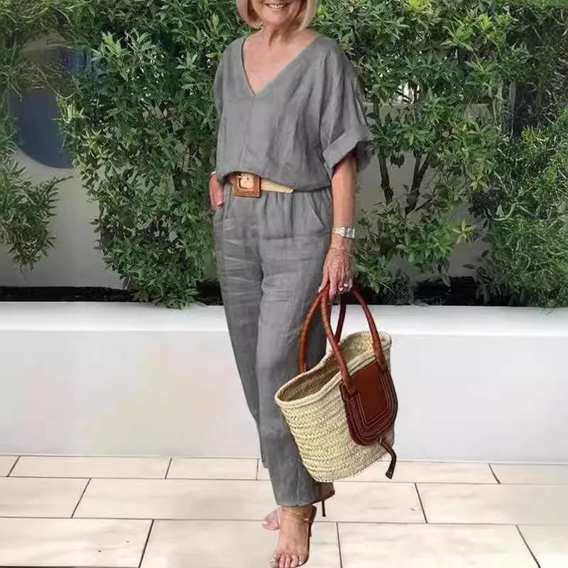 Woman in casual gray outfit holding a straw tote bag outdoors.