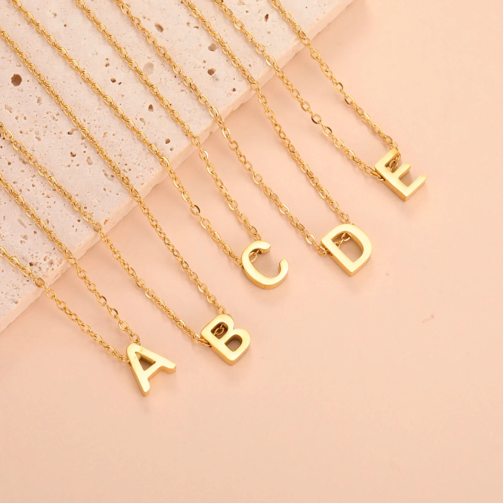 Gold necklaces with alphabet letter pendants A, B, C, D, E.
