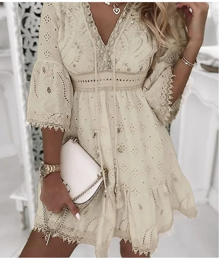 Woman in a cream lace dress holding a white clutch.