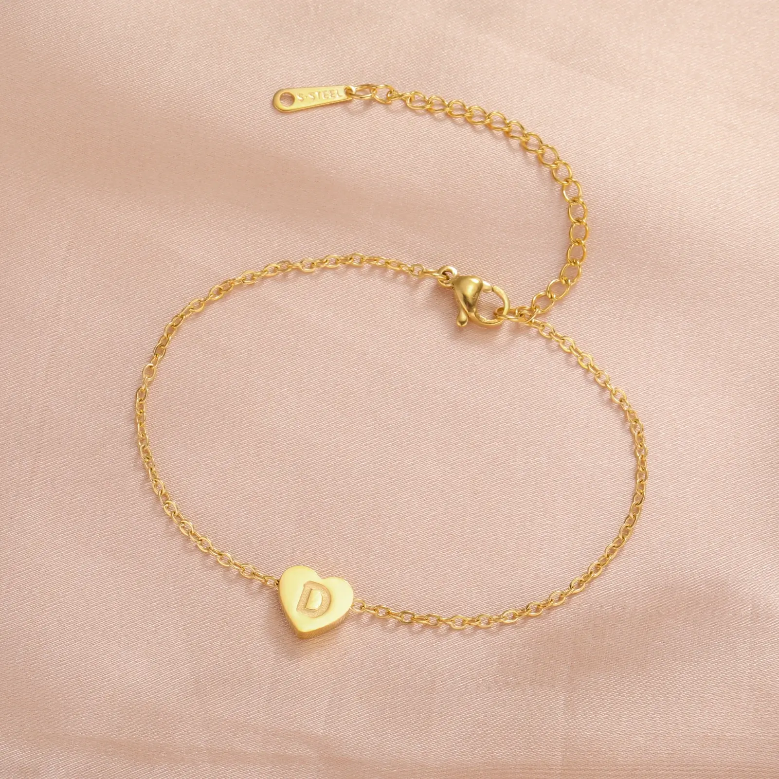 Delicate gold heart bracelet with a subtle engraved initial.